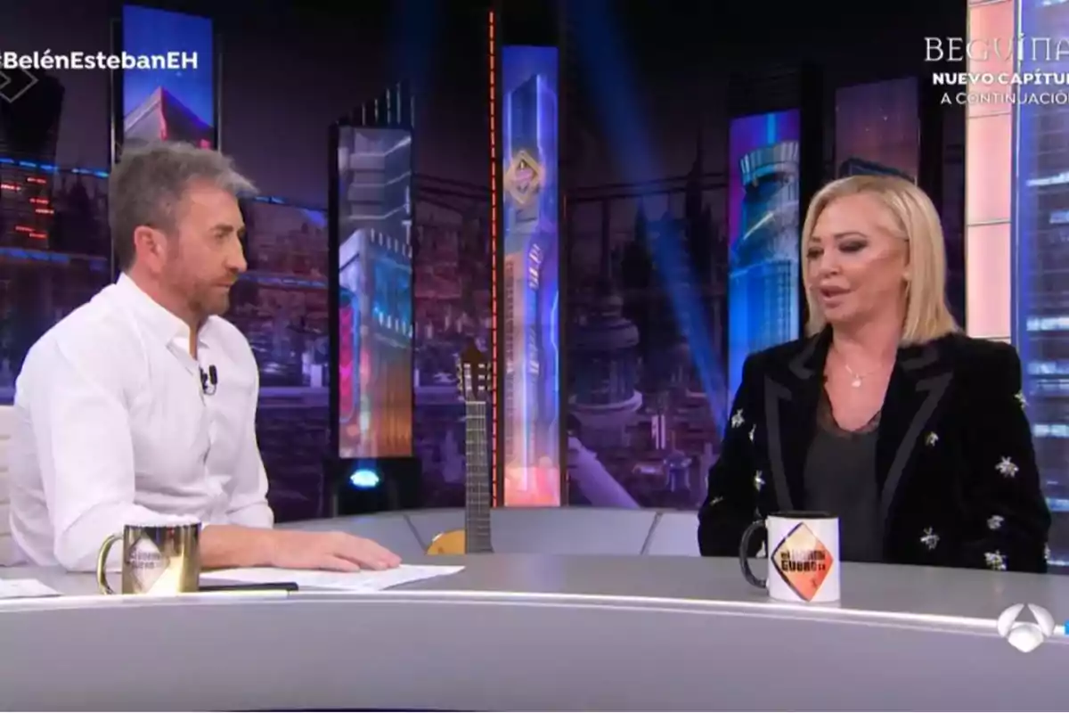 Pablo Motos y Belén Esteban conversan en un set de televisión con una decoración futurista y tazas sobre la mesa. Pablo Motos y Belén Esteban conversan en un set de televisión con una decoración futurista y tazas sobre la mesa.
