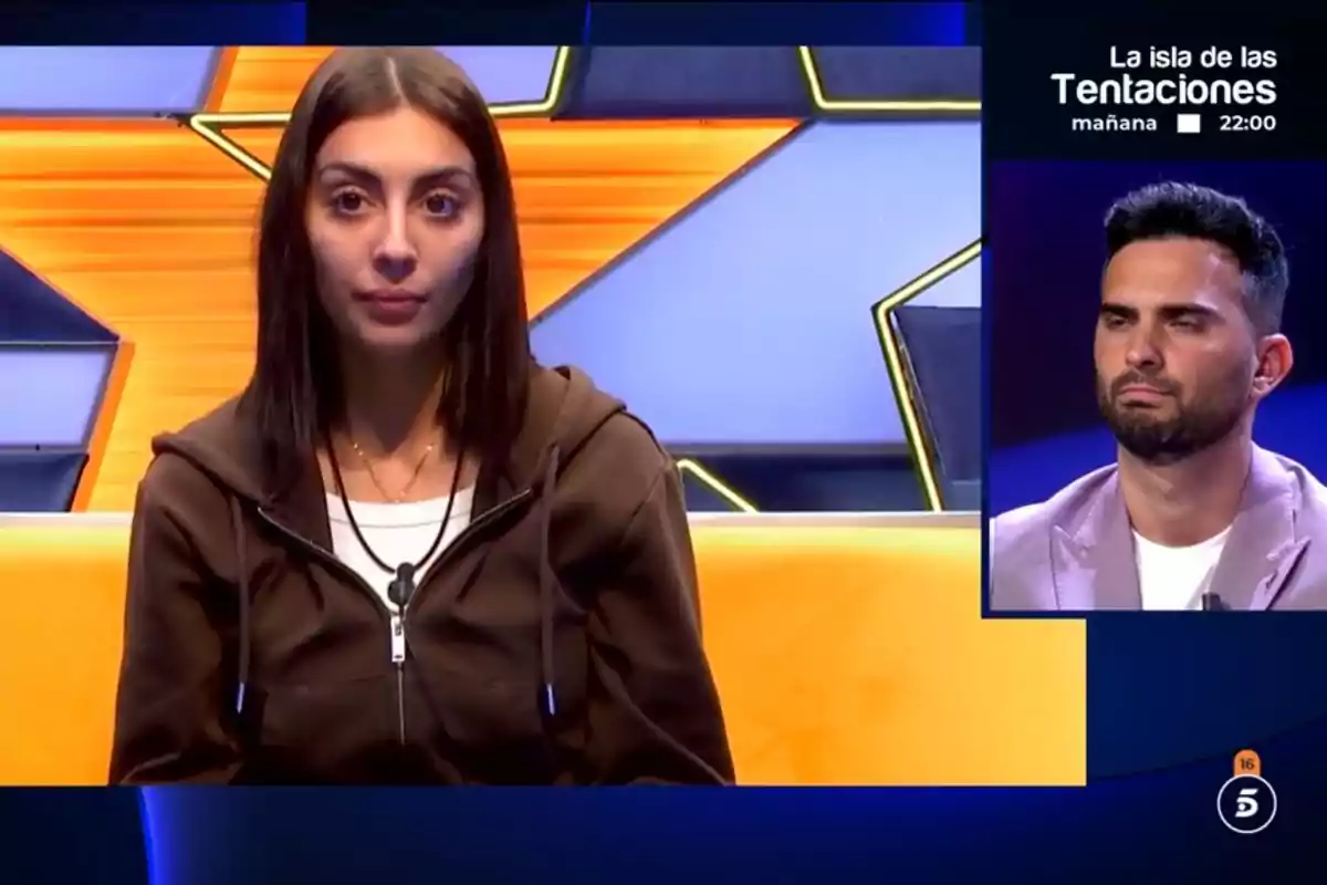 Marieta con sudadera marrón está sentada frente a una pantalla con un fondo de estrella amarilla, mientras Suso Álvarez aparece en un recuadro pequeño a la derecha; en la esquina superior derecha se anuncia un programa de televisión.