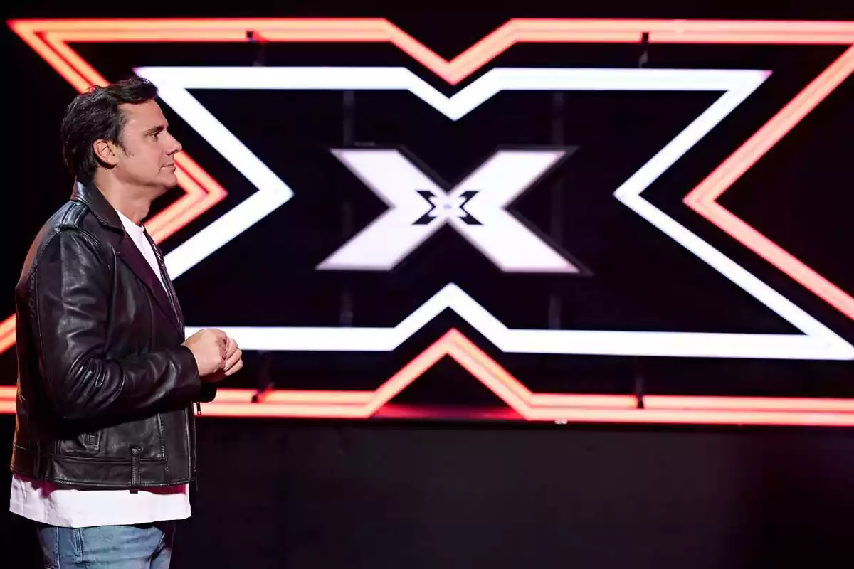 Fotografía de Ion Aramendi de perfil delante del logo de Factor X Fotografía de Ion Aramendi de perfil delante del logo de Factor X