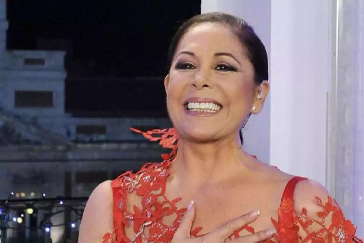 Una mujer sonriente con un vestido rojo decorado con encaje en un entorno nocturno.