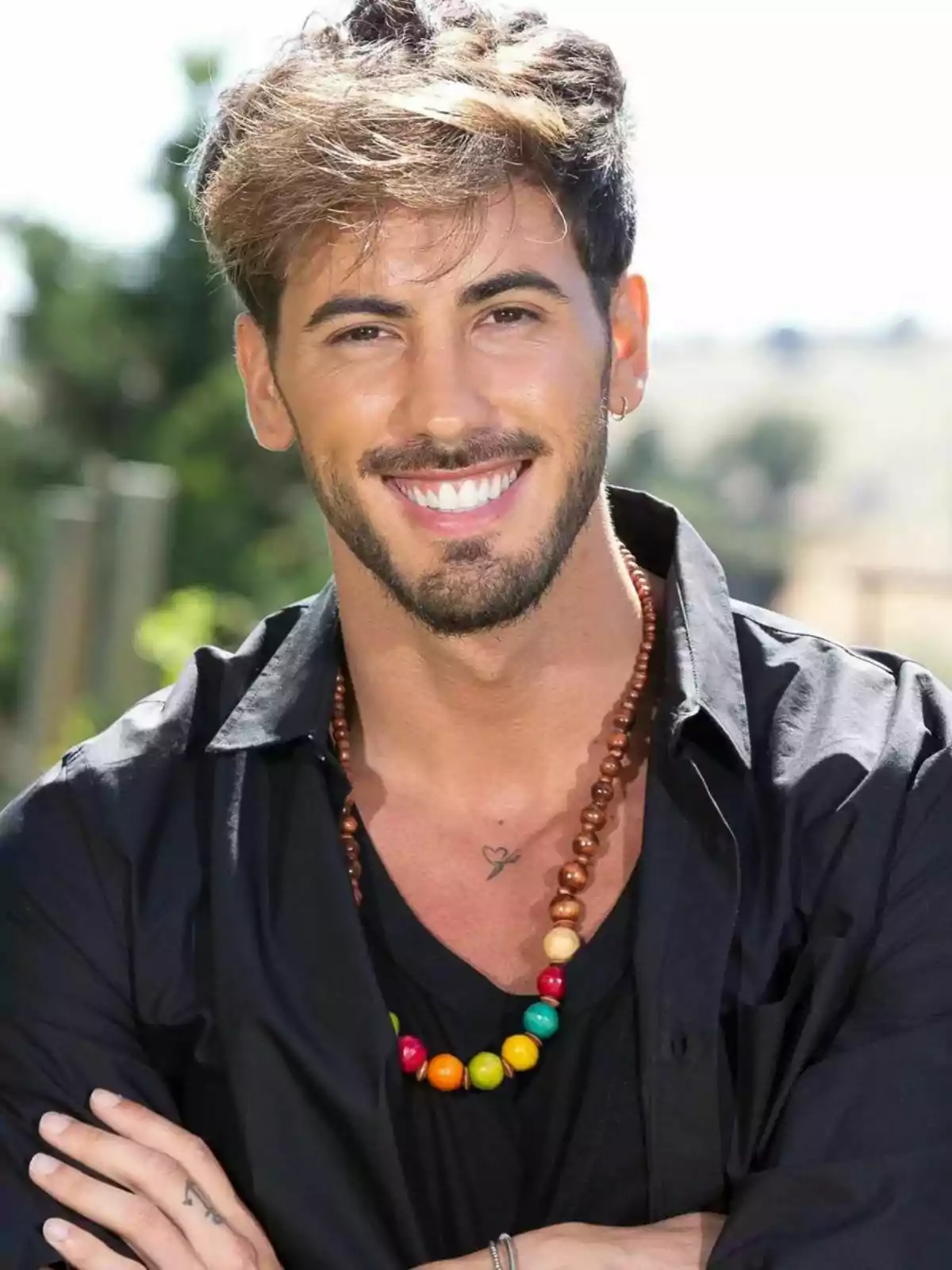 Iván González sonriendo, lleva una camisa negra y un collar de cuentas de colores. Iván González sonriendo, lleva una camisa negra y un collar de cuentas de colores.