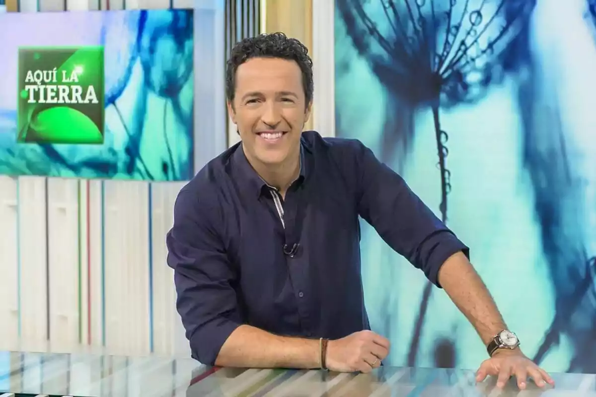 Jacob Petrus somrient en un plató de televisió amb el logotip d' Jacob Petrus somrient en un plató de televisió amb el logotip d'