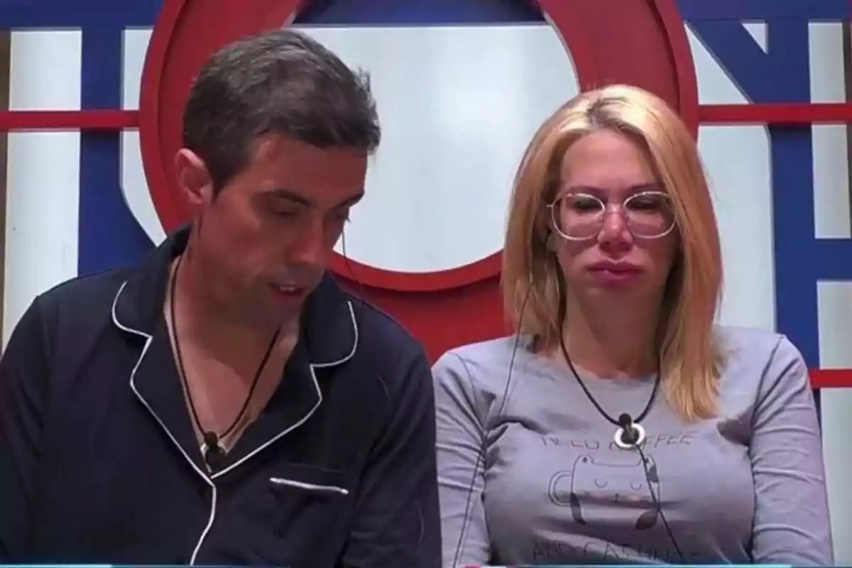 Javi i Vanessa, una dona amb ulleres i un home amb pijama fosc, tots dos amb micròfons, al confessionari de Gran Hermano. Javi i Vanessa, una dona amb ulleres i un home amb pijama fosc, tots dos amb micròfons, al confessionari de Gran Hermano.