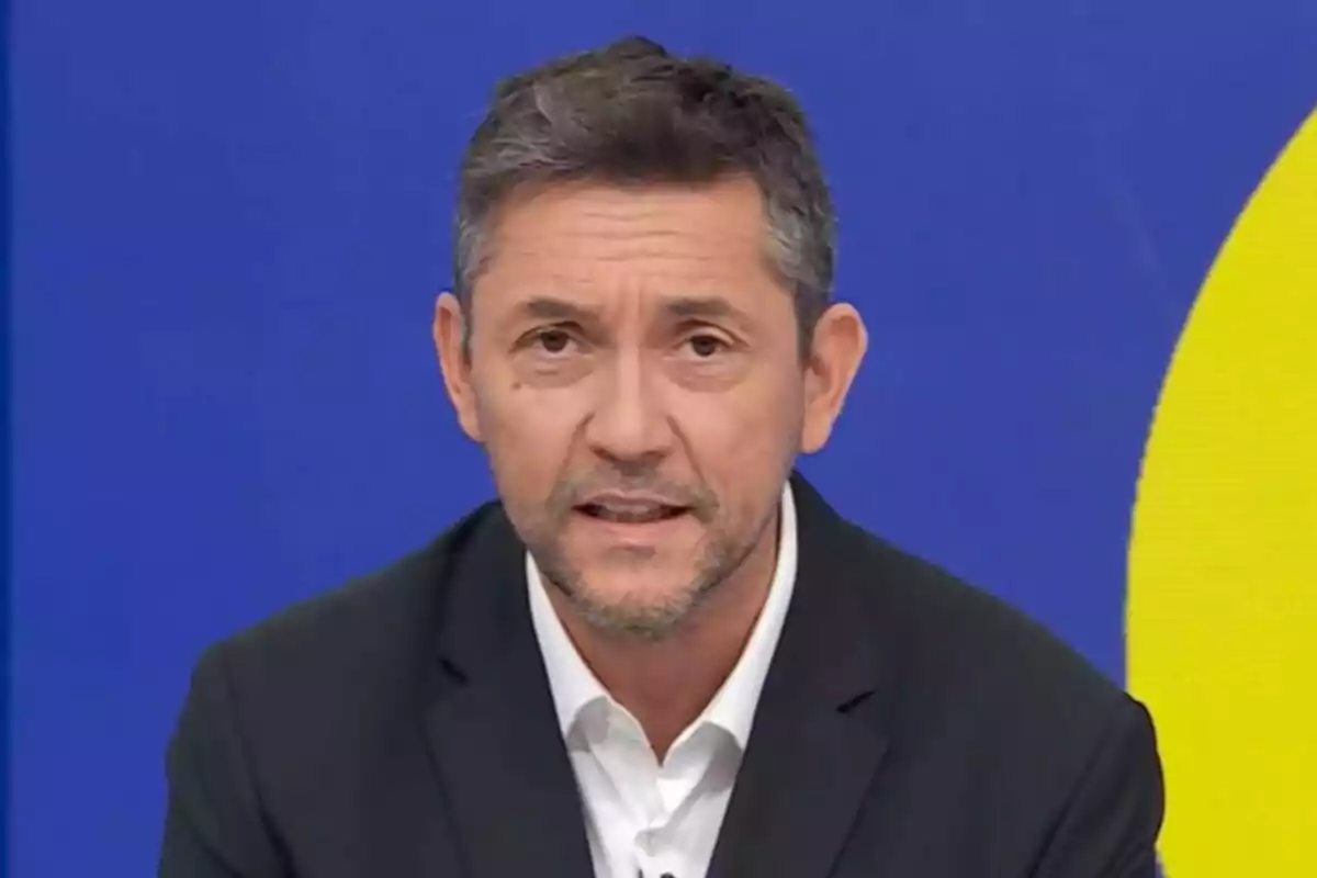 Javier Ruiz amb barba i cabell curt, vestit amb un vestit fosc i camisa blanca, està parlant davant d'un fons blau i groc a Mañaneros 360. Javier Ruiz amb barba i cabell curt, vestit amb un vestit fosc i camisa blanca, està parlant davant d'un fons blau i groc a Mañaneros 360.