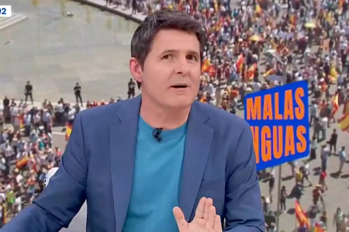 Jesús Cintora amb jaqueta blava i samarreta turquesa està parlant davant d'una multitud en una manifestació, amb un cartell que diu 