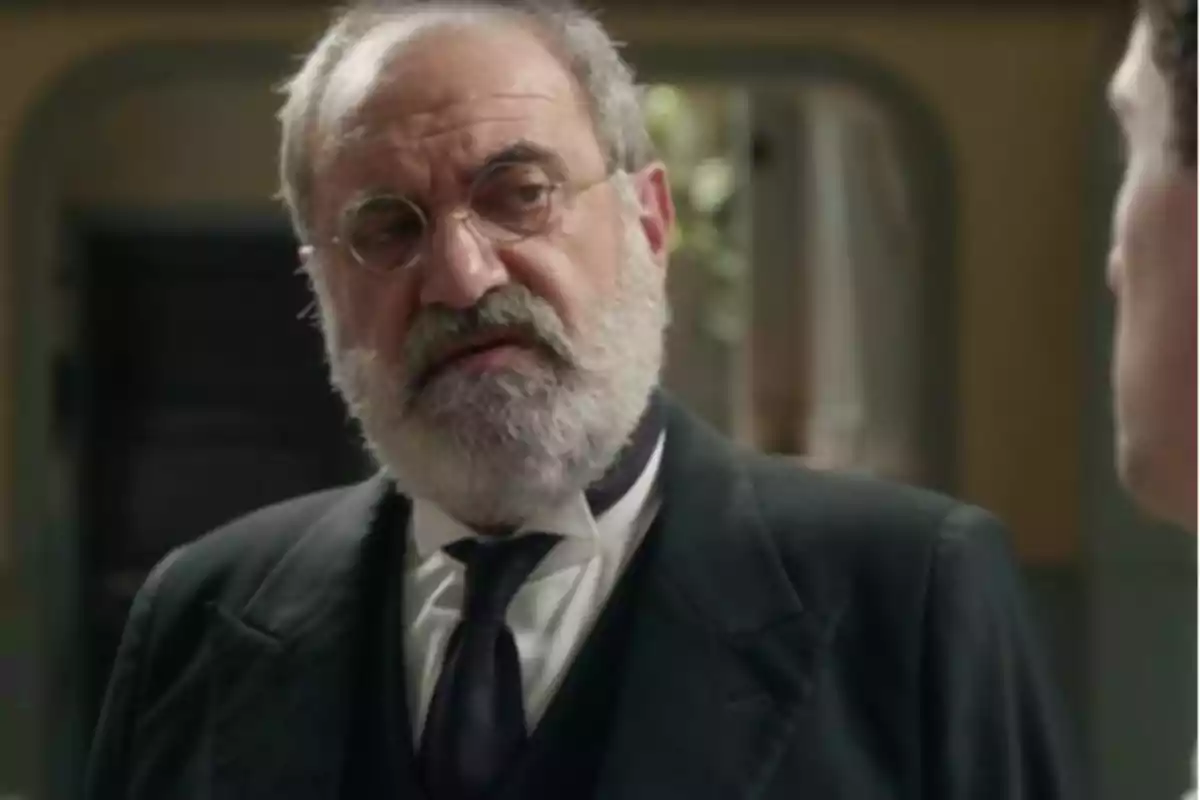 Joaquín Climent con barba blanca y gafas redondas, vestido con traje oscuro y corbata, mirando hacia la derecha. Joaquín Climent con barba blanca y gafas redondas, vestido con traje oscuro y corbata, mirando hacia la derecha.