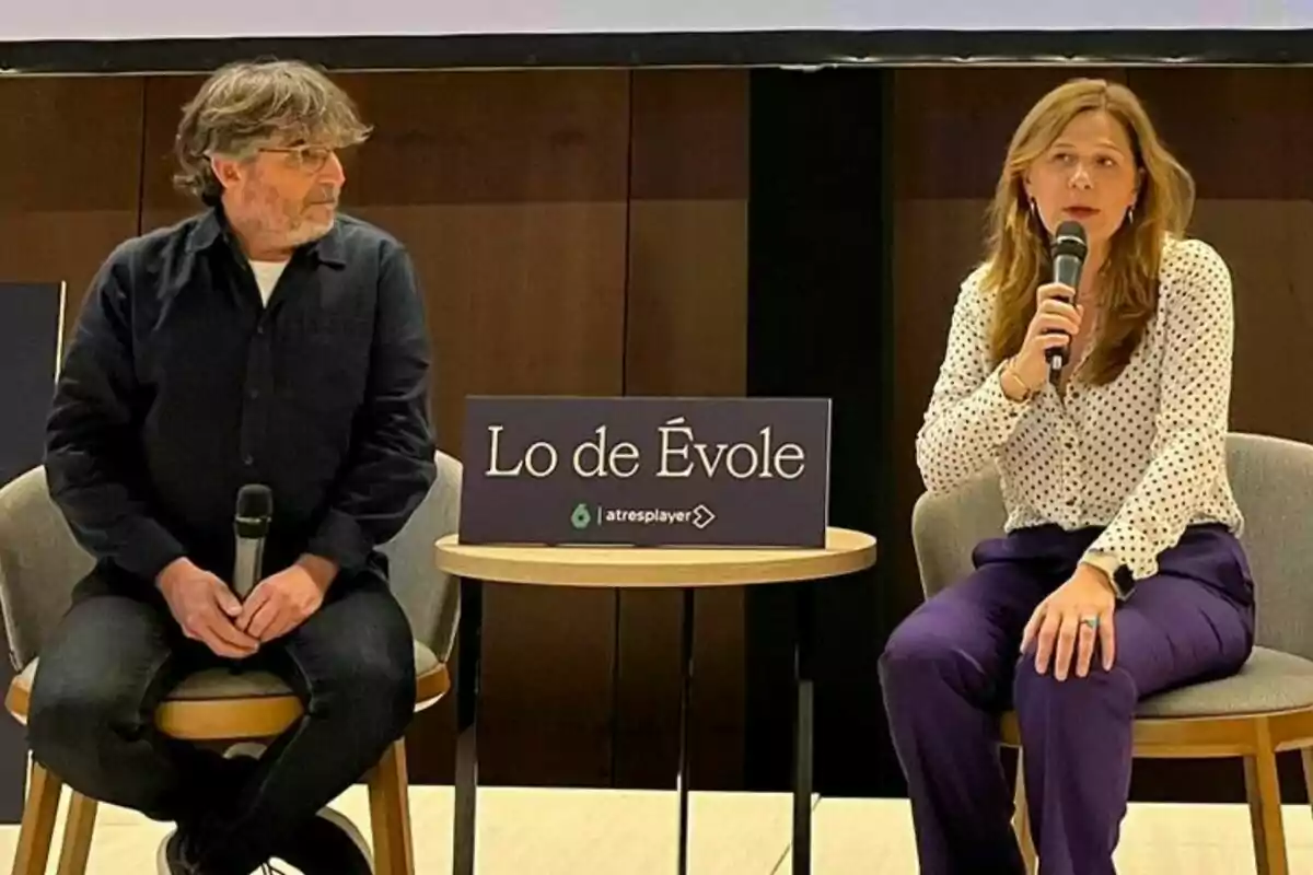 Jordi Évole i Carmen Ferreiro assegudes en cadires amb micròfons a la mà, entre elles hi ha una taula petita amb un cartell que diu "Lo de Évole".