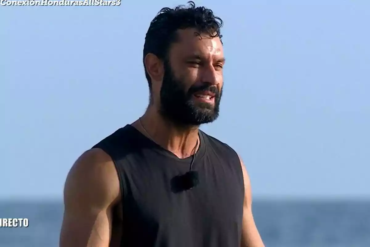 Fotografía de Jorge Pérez con barba y cabello rizado, vistiendo una camiseta sin mangas negra, con el cielo azul de fondo en el puente de las emociones de Supervivientes Fotografía de Jorge Pérez con barba y cabello rizado, vistiendo una camiseta sin mangas negra, con el cielo azul de fondo en el puente de las emociones de Supervivientes