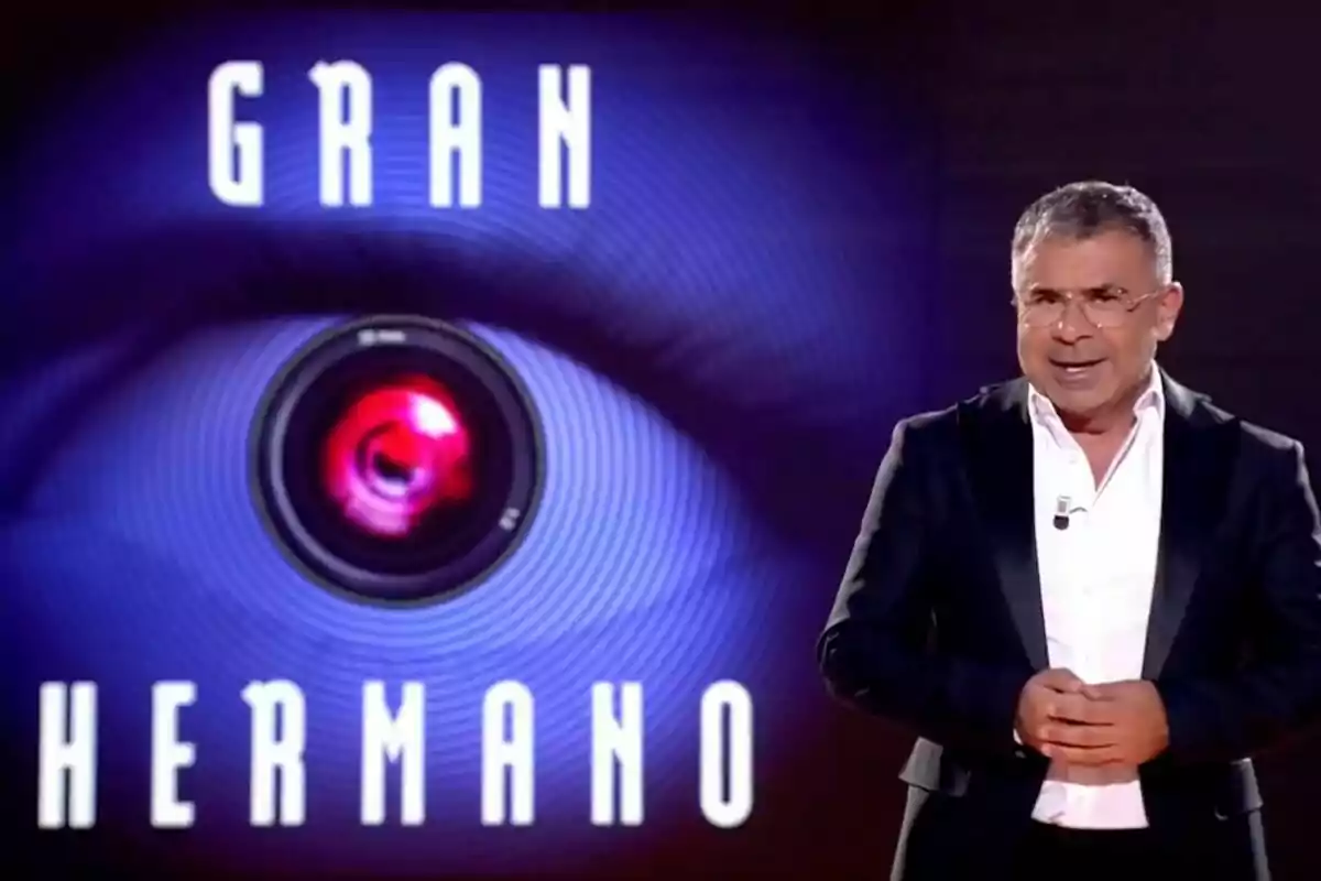 Jorge Javier Vázquez amb un vestit fosc i camisa blanca, al costat d'un logotip que diu Jorge Javier Vázquez amb un vestit fosc i camisa blanca, al costat d'un logotip que diu