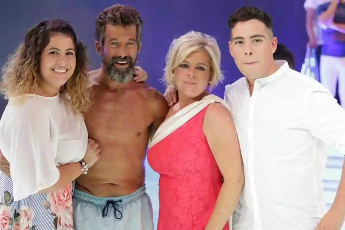 Un grupo de cuatro personas posando para una foto, con una mujer de cabello rizado y blusa blanca a la izquierda, un hombre sin camisa en el centro, una mujer rubia con vestido rosa a su lado y un hombre con camisa blanca a la derecha. Un grupo de cuatro personas posando para una foto, con una mujer de cabello rizado y blusa blanca a la izquierda, un hombre sin camisa en el centro, una mujer rubia con vestido rosa a su lado y un hombre con camisa blanca a la derecha.