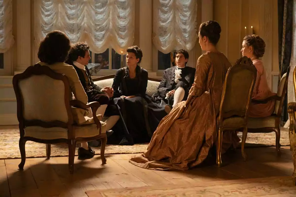 Un grupo de personas vestidas con trajes de época están sentadas en una sala elegantemente decorada, conversando entre ellas y dos de ellas son José Luis y Victoria de 'Valle Salvaje'. Un grupo de personas vestidas con trajes de época están sentadas en una sala elegantemente decorada, conversando entre ellas y dos de ellas son José Luis y Victoria de 'Valle Salvaje'.