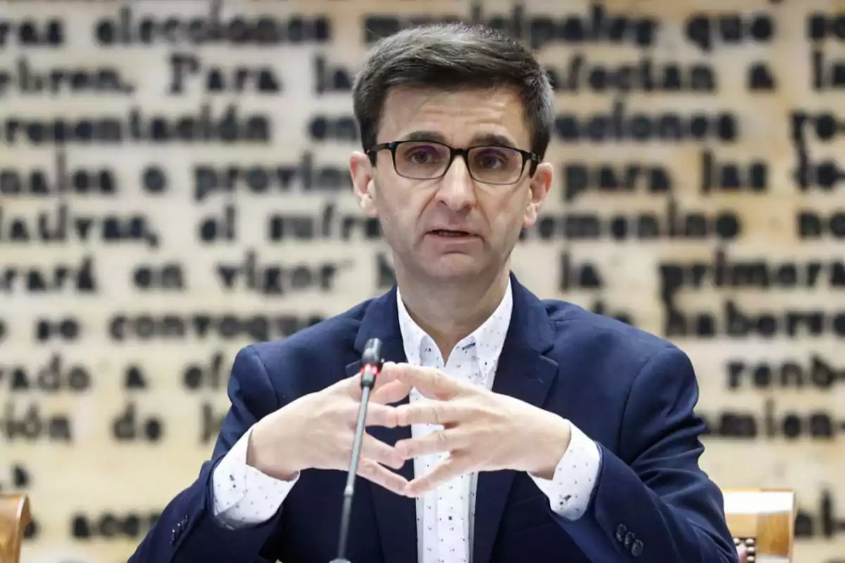 Jose Pablo Lopez, president de RTVE, parla en un micròfon amb un fons de text borros.
