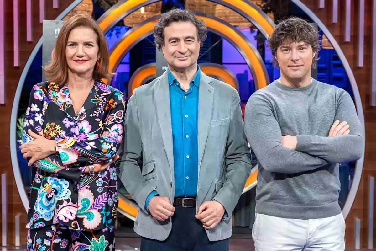 Pepe Rodríguez, Samantha Vallejo-Nágera y Jordi Cruz posan frente a un fondo colorido con un diseño circular, una mujer lleva un conjunto floral, un hombre viste una chaqueta azul claro y otro hombre lleva un suéter gris en MasterChef. Pepe Rodríguez, Samantha Vallejo-Nágera y Jordi Cruz posan frente a un fondo colorido con un diseño circular, una mujer lleva un conjunto floral, un hombre viste una chaqueta azul claro y otro hombre lleva un suéter gris en MasterChef.