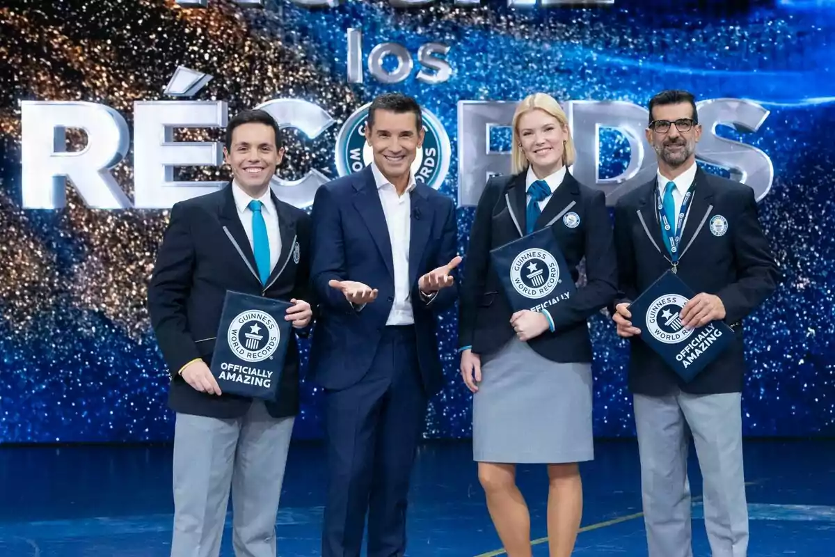 Els jutges i Jesús Vázquez posant en un escenari amb el logotip de Guinness World Records al fons, tots vestits amb vestits formals i somrient a la càmera.