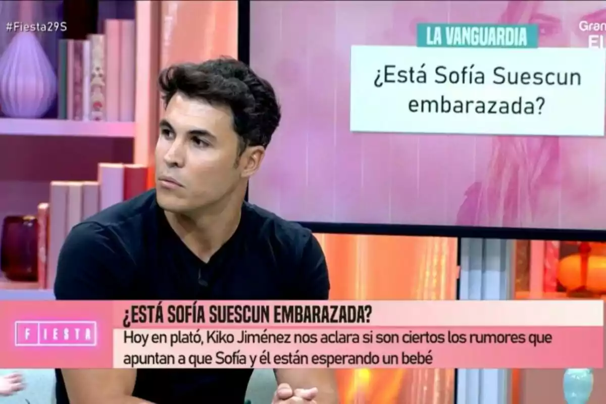 Kiko Jiménez sentado en el plató de Fiesta con un rótulo que pregunta Kiko Jiménez sentado en el plató de Fiesta con un rótulo que pregunta