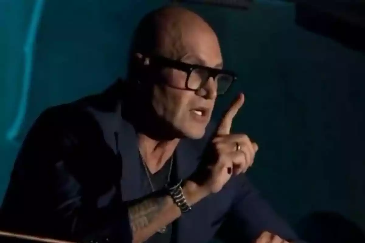 Kiko Matamoros calvo con gafas y tatuaje en el brazo levanta un dedo mientras habla apasionadamente en 'La Revuelta'.