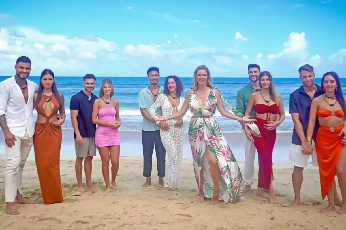 Las cinco parejas de La Isla de las Tentaciones posando en la playa con Sandra Barneda y el mar de fondo.