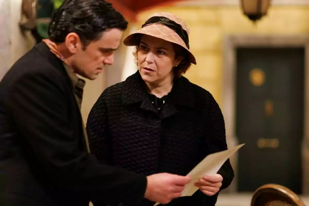 Pietro y Antonia conversan mientras miran un documento en un entorno interior. Captura de 'La Moderna' Pietro y Antonia conversan mientras miran un documento en un entorno interior. Captura de 'La Moderna'