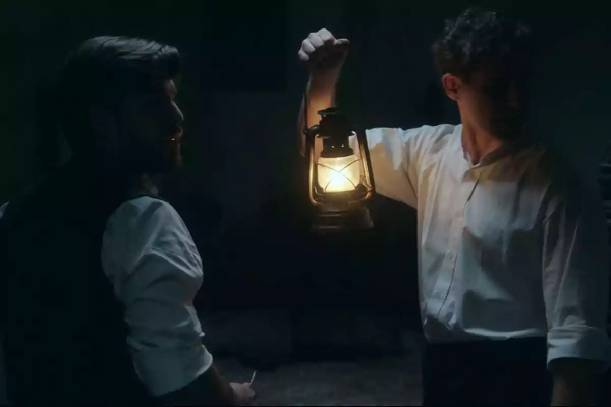 Lope y Marcelo en una habitación oscura sostienen una lámpara de aceite que ilumina suavemente el entorno. Captura de 'La Promesa' Lope y Marcelo en una habitación oscura sostienen una lámpara de aceite que ilumina suavemente el entorno. Captura de 'La Promesa'