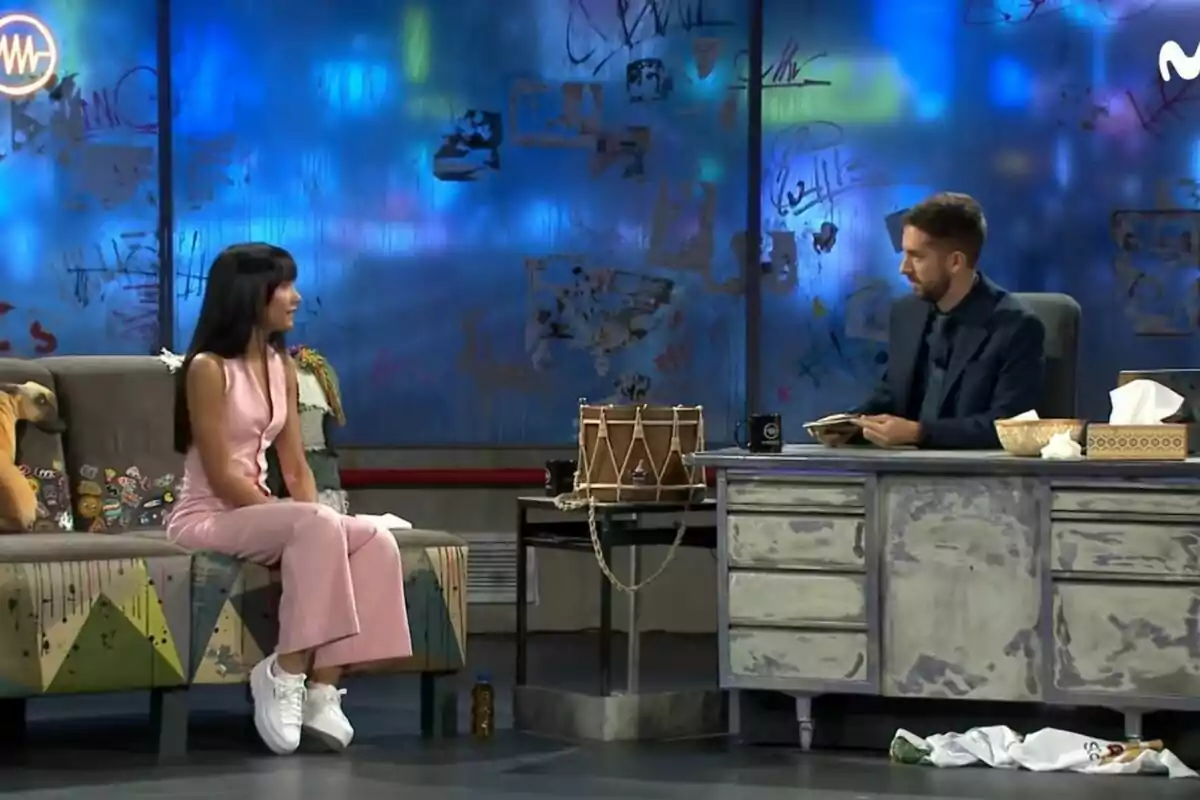 Aitana amb un vestit rosa i sabatilles blanques està asseguda en un sofà, mentre que David Broncano amb vestit fosc està assegut darrere d'un escriptori en un set de televisió amb fons blau i grafits. Captura de 'La Resistència' el 16 de setembre de 2021 Aitana amb un vestit rosa i sabatilles blanques està asseguda en un sofà, mentre que David Broncano amb vestit fosc està assegut darrere d'un escriptori en un set de televisió amb fons blau i grafits. Captura de 'La Resistència' el 16 de setembre de 2021