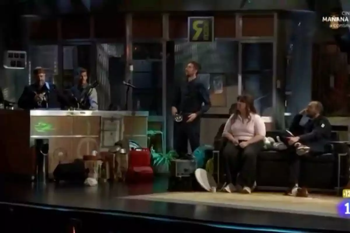 El equipo de 'La Revuelta' en un set de televisión, con Grison y Castella tocando instrumentos detrás de un mostrador y David Broncano, LalaChus y Jorge Ponce sentados en un sofá, rodeados de varios objetos y decoraciones. El equipo de 'La Revuelta' en un set de televisión, con Grison y Castella tocando instrumentos detrás de un mostrador y David Broncano, LalaChus y Jorge Ponce sentados en un sofá, rodeados de varios objetos y decoraciones.