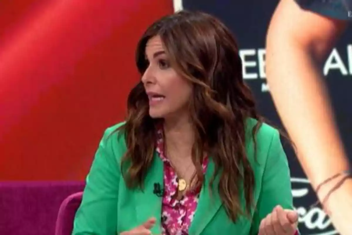 Nuria Roca, vestida con un blazer verde y blusa floral, hablando en un programa de televisión con fondo rojo. Captura de 'La Roca'