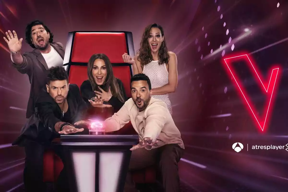 Eva González, Antonio Orozco, Malú, Luis Fonsi y Pablo López posan emocionadas alrededor de una silla roja con un botón iluminado en el centro, con un fondo oscuro y un logotipo de La Voz en la esquina superior derecha. Eva González, Antonio Orozco, Malú, Luis Fonsi y Pablo López posan emocionadas alrededor de una silla roja con un botón iluminado en el centro, con un fondo oscuro y un logotipo de La Voz en la esquina superior derecha.