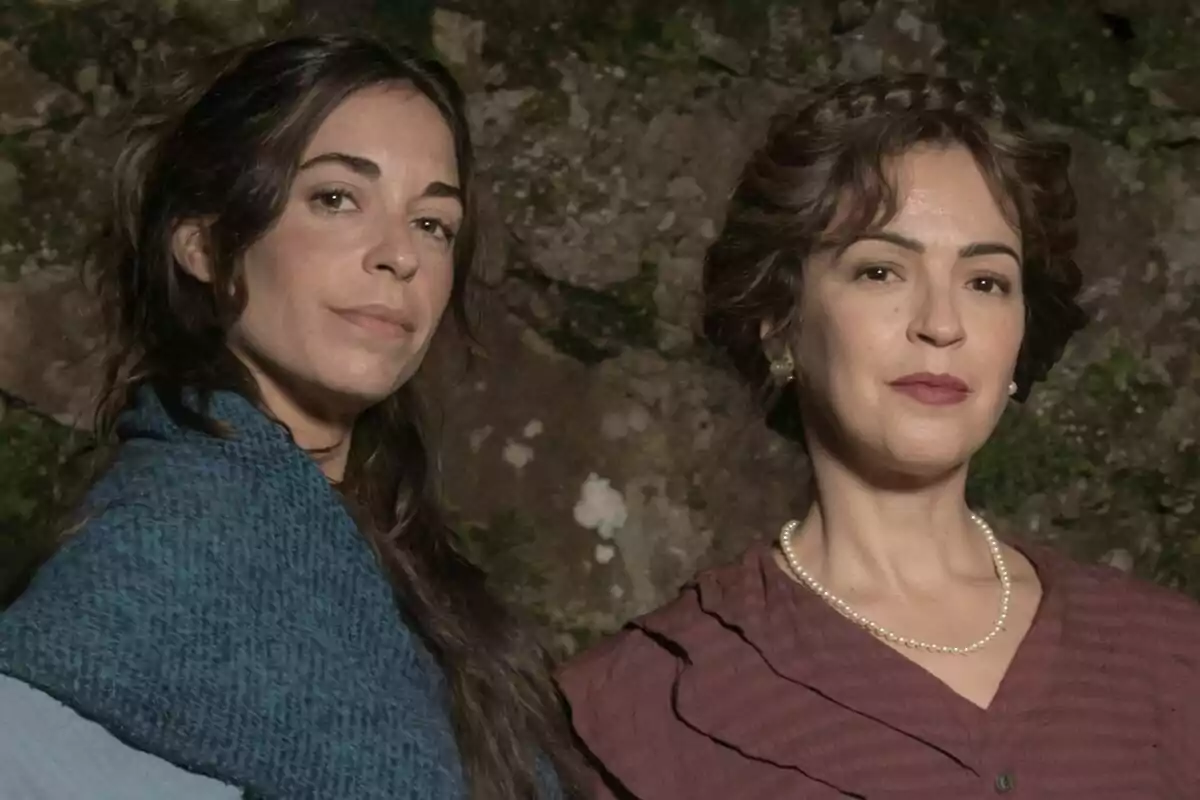 Veronica Sánchez y Carlota Baró posan juntas frente a un fondo de piedra, una lleva un chal azul y la otra un collar de perlas en el rodaje de Las hijas de la criada.