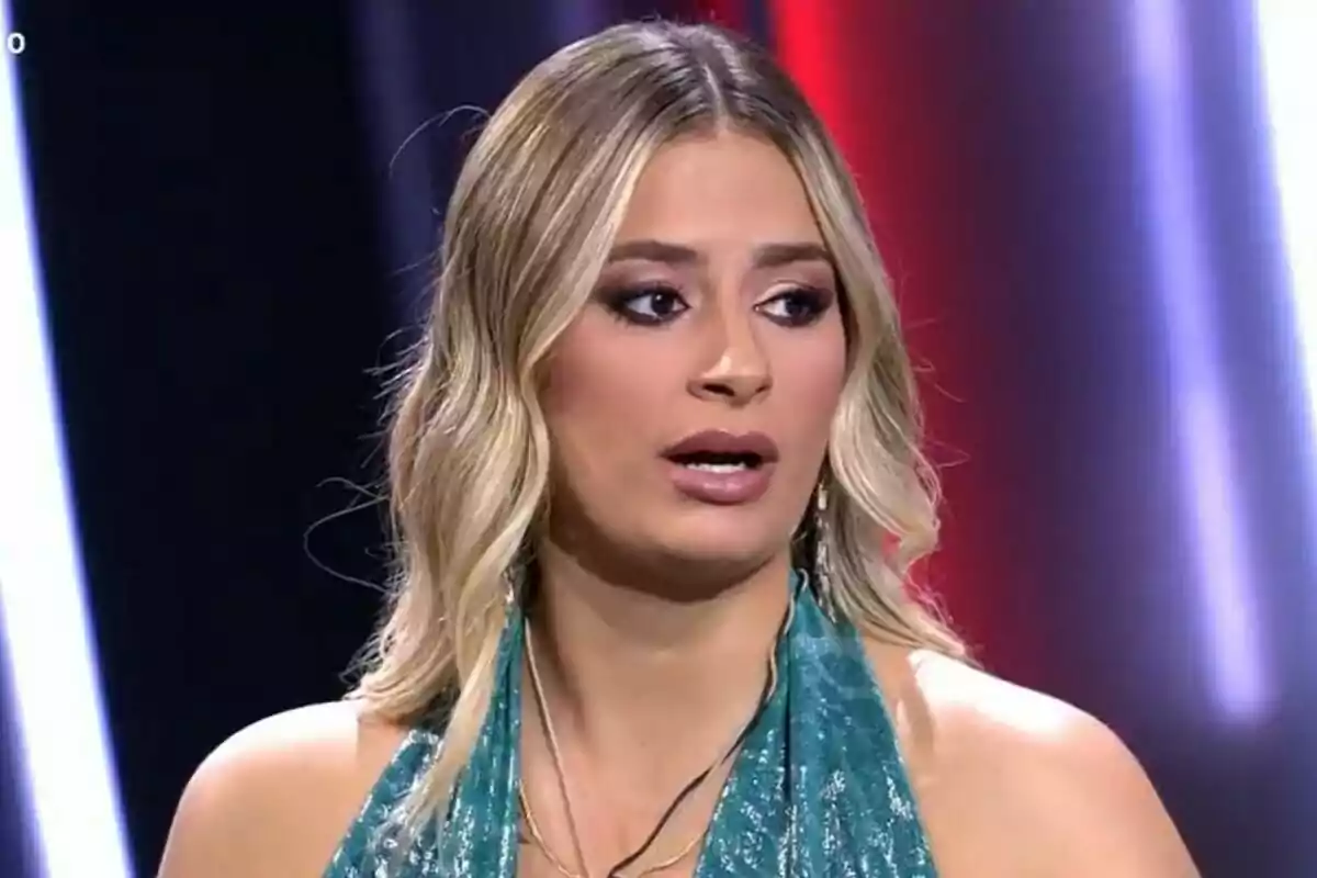 Laura Galera con cabello rubio y vestido azul en un entorno iluminado en el plató de Gran Hermano. Laura Galera con cabello rubio y vestido azul en un entorno iluminado en el plató de Gran Hermano.