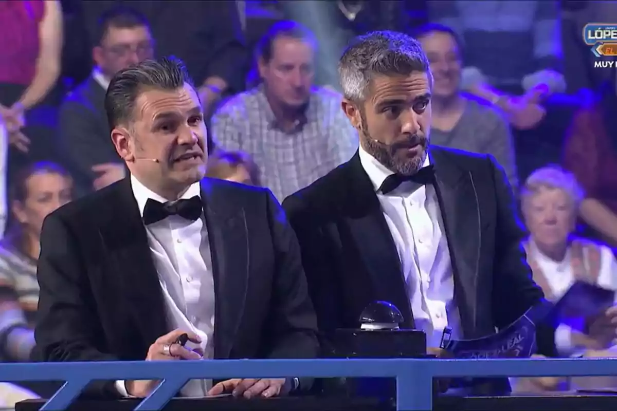 Captura de Roberto Leal i Iñaki López vestits d'esmòquing estan en un escenari, un sosté un bolígraf i l'altre un paper, mentre el públic observa des del fons López i Leal contra el canal. Captura de Roberto Leal i Iñaki López vestits d'esmòquing estan en un escenari, un sosté un bolígraf i l'altre un paper, mentre el públic observa des del fons López i Leal contra el canal.