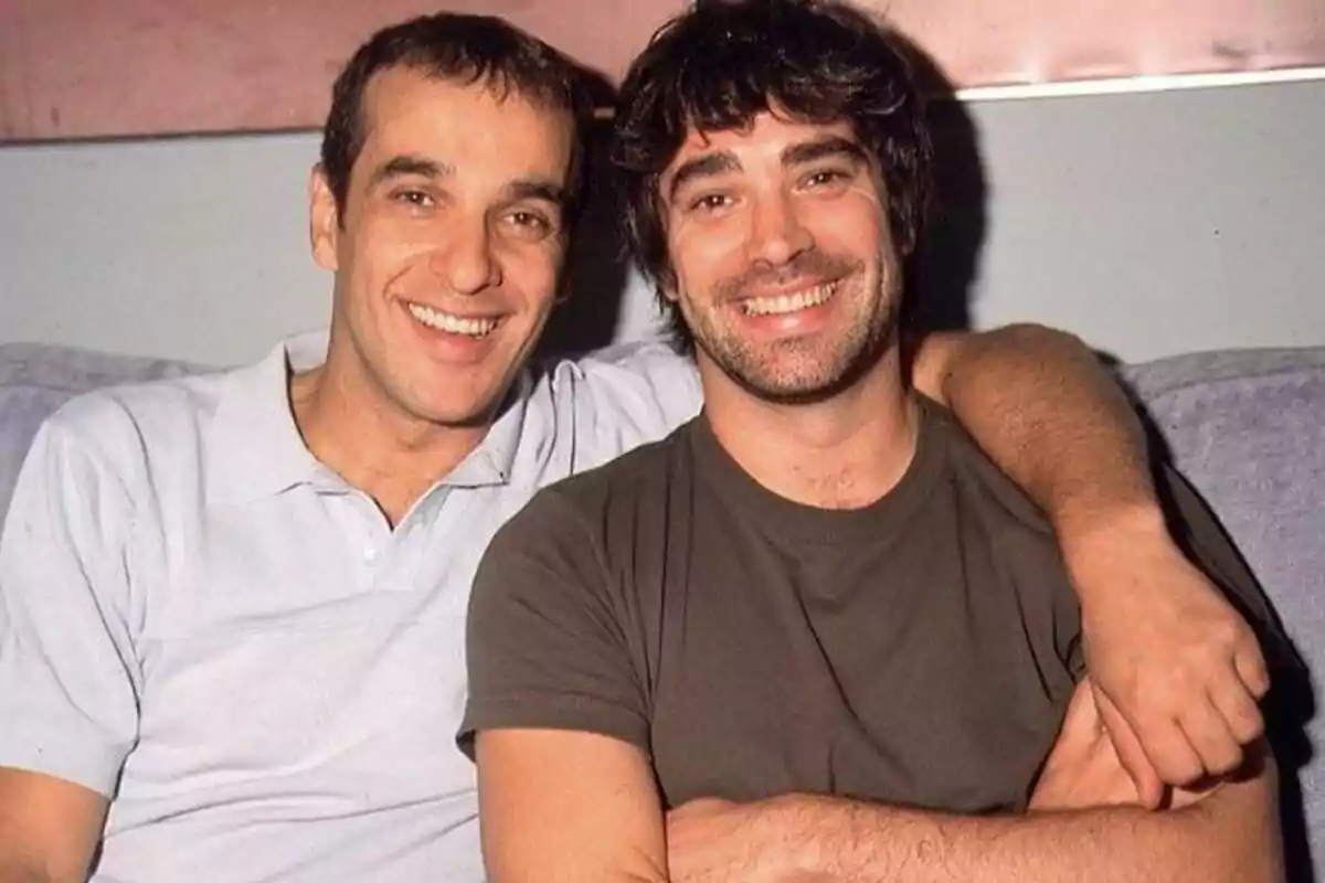 Captura de Luis Merlo y Adrià Collado como Mauri y Fernando sonrientes sentados en un sofá, uno con camiseta gris y el otro con camiseta marrón, abrazándose y mirando a la cámara en Aquí no hay quien viva. Captura de Luis Merlo y Adrià Collado como Mauri y Fernando sonrientes sentados en un sofá, uno con camiseta gris y el otro con camiseta marrón, abrazándose y mirando a la cámara en Aquí no hay quien viva.