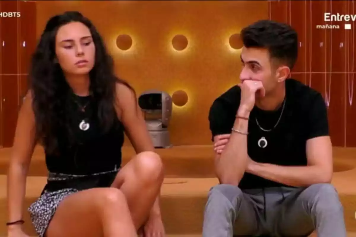 Nerea i Luis asseguts en un sofà amb fons taronja i llums circulars a Gran Hermano. Nerea i Luis asseguts en un sofà amb fons taronja i llums circulars a Gran Hermano.
