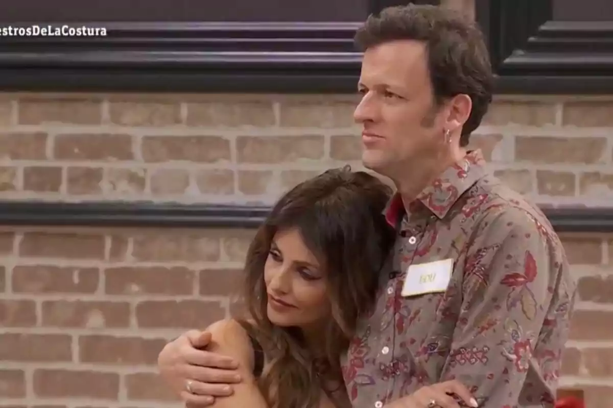 Mónica Cruz y Edu Soto se abrazan en un entorno interior con una pared de ladrillos al fondo en 'Maestros de la Costura Celebrity'.