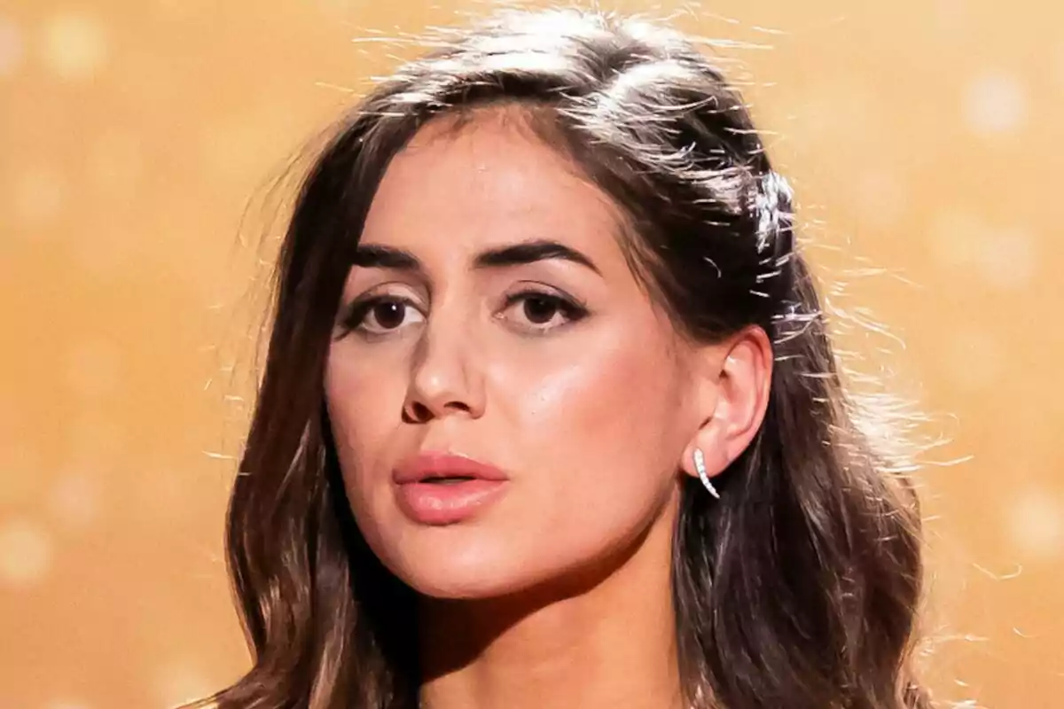 Maica Benedicto con cabello castaño y aretes brillantes en un fondo dorado en la final de GH DÚO.