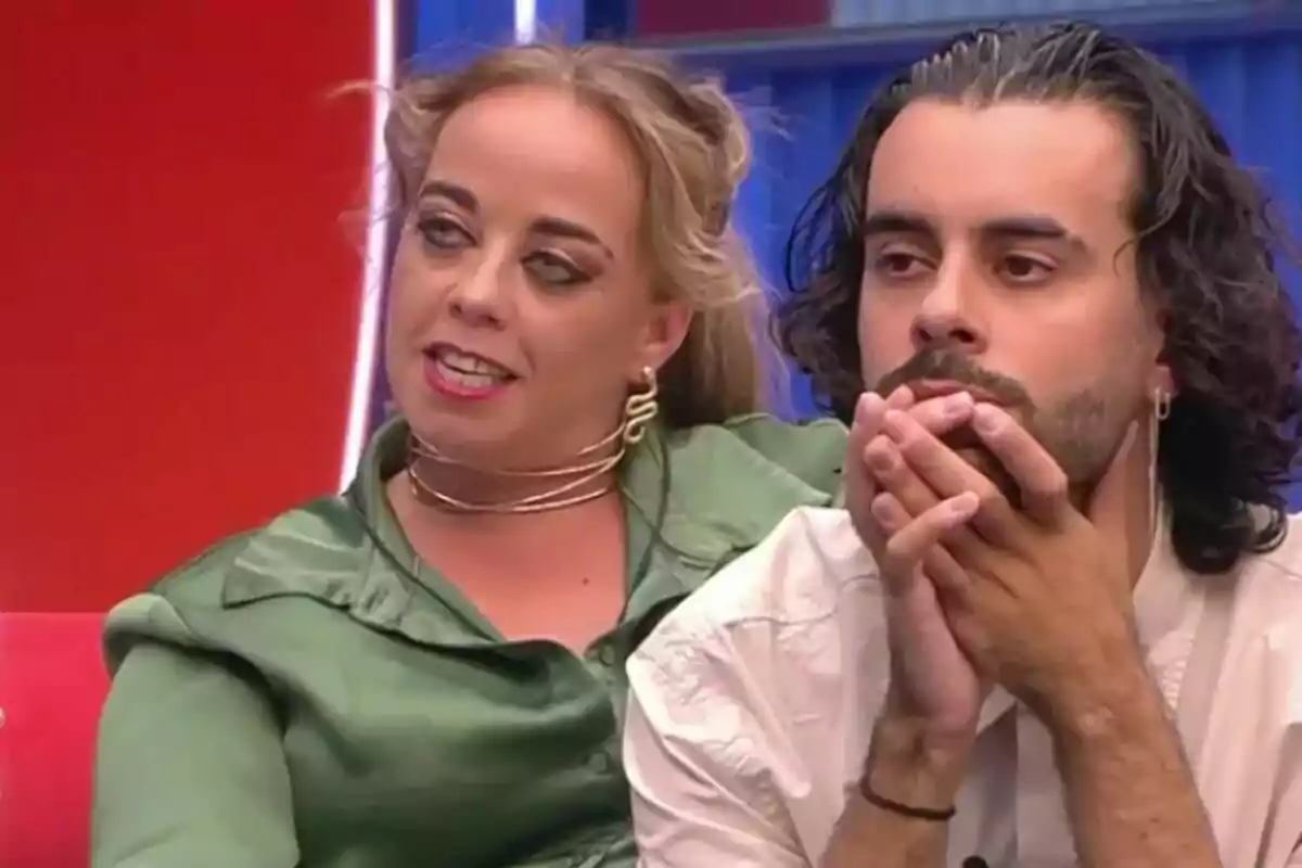 Maite i Ruvens asseguts en un sofà, una dona amb brusa verda i un home amb camisa blanca, tots dos mirant endavant, a la casa de Gran Hermano. Maite i Ruvens asseguts en un sofà, una dona amb brusa verda i un home amb camisa blanca, tots dos mirant endavant, a la casa de Gran Hermano.