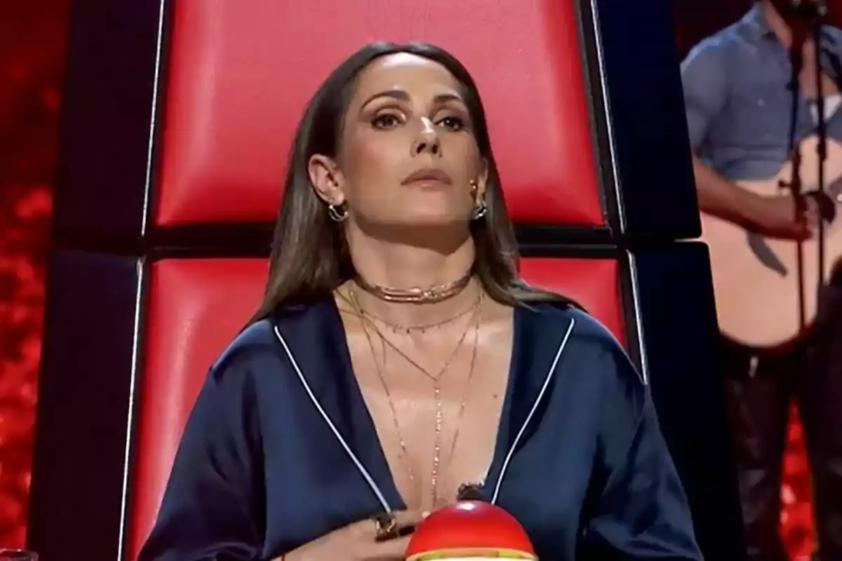 Malú sentada en una silla roja de La Voz con un botón rojo frente a ella. Malú sentada en una silla roja de La Voz con un botón rojo frente a ella.