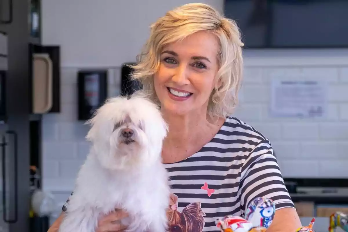 Mar Vega sonriente con cabello rubio corto sostiene a un perro pequeño y peludo en sus brazos, ambos están en un entorno interior en Patas Arriba. Mar Vega sonriente con cabello rubio corto sostiene a un perro pequeño y peludo en sus brazos, ambos están en un entorno interior en Patas Arriba.