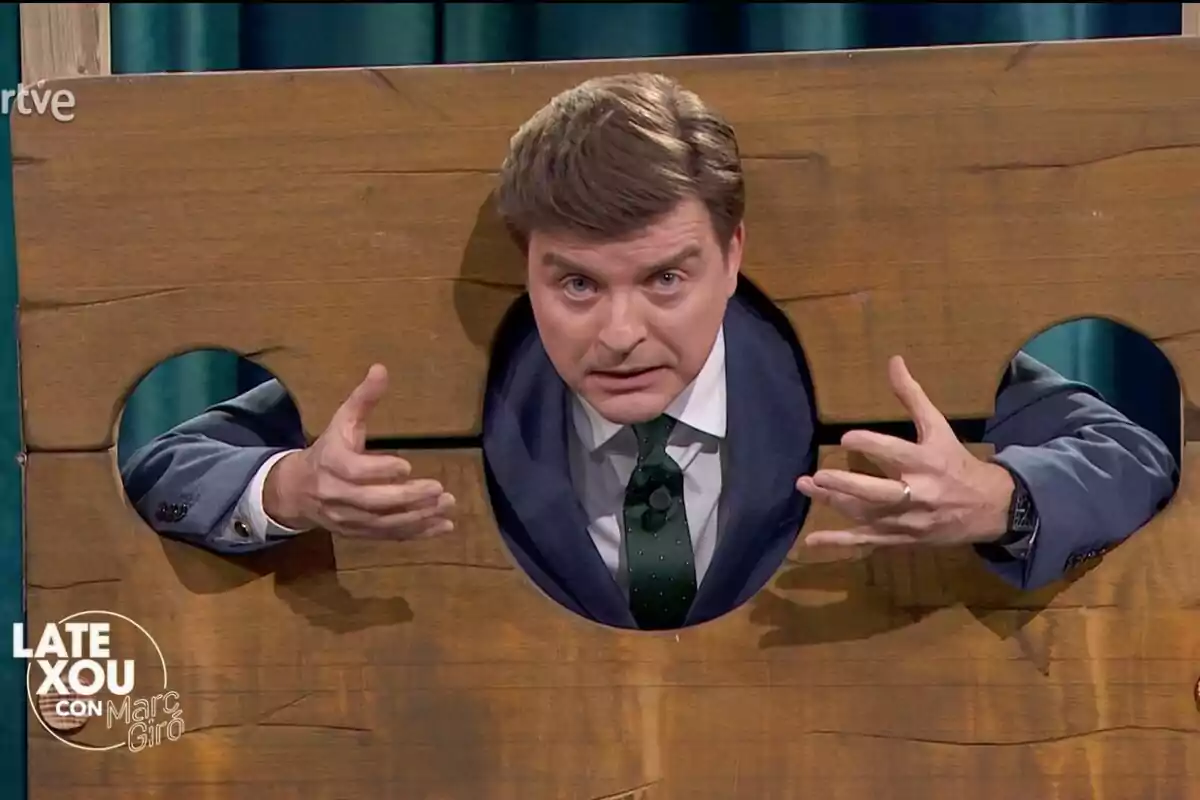 Marc Giró amb vestit i corbata està en un cep de fusta a 'Late Xou amb Marc Giró'.