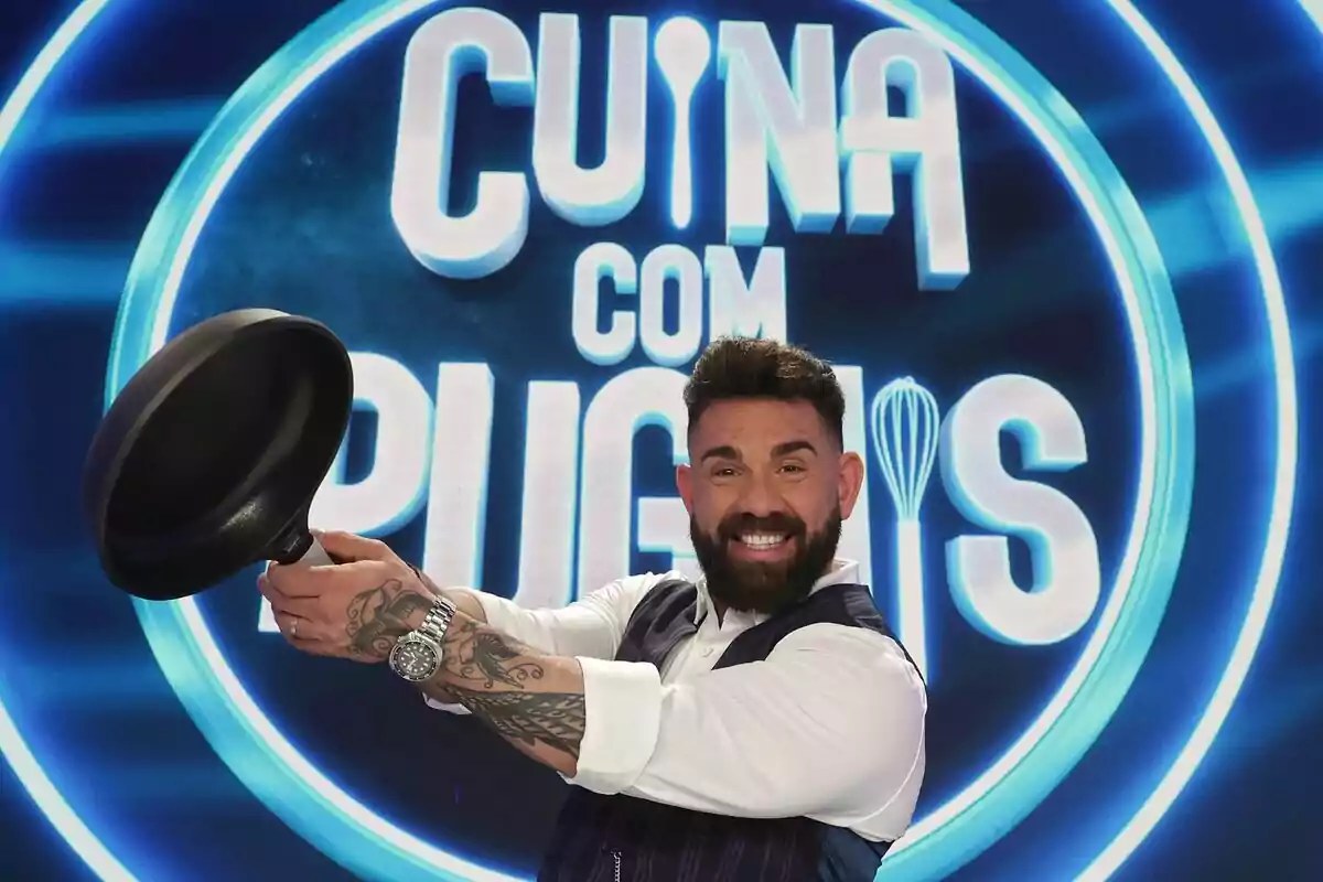 Fotografia de Marc Ribas amb una paella com a presentador de Cuina com puguis de TV3 Fotografia de Marc Ribas amb una paella com a presentador de Cuina com puguis de TV3