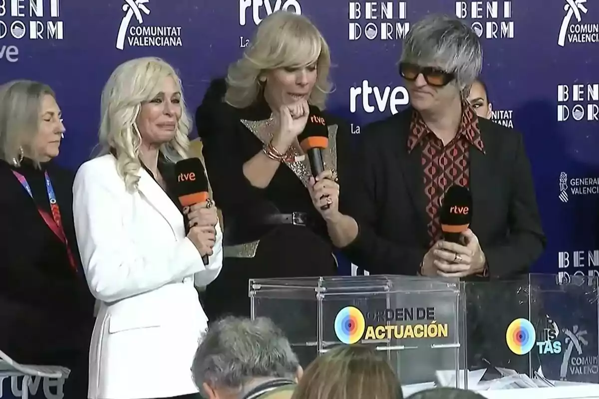 Un grupo de personas sosteniendo micrófonos en un evento con fondo azul que tiene logotipos de RTVE y Benidorm.