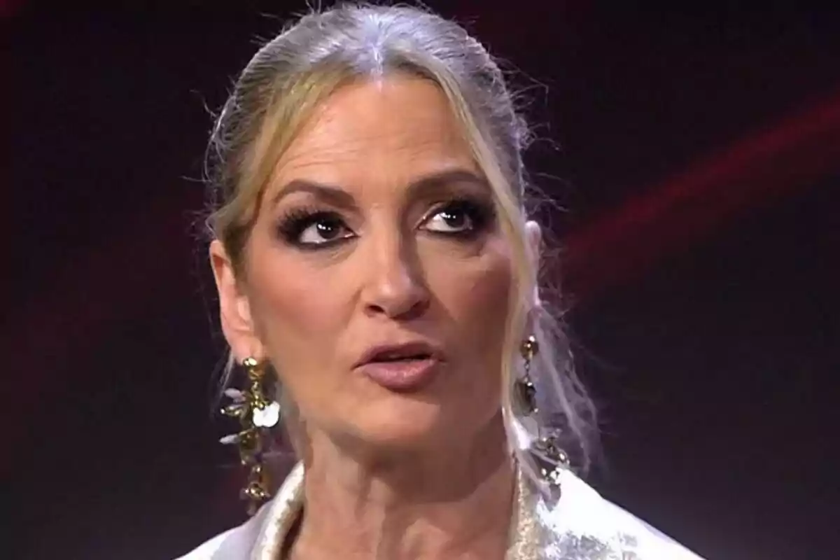 Pla curt de María José Galera amb cabell ros recollit i arracades grans, mirant cap amunt amb expressió seriosa. Pla curt de María José Galera amb cabell ros recollit i arracades grans, mirant cap amunt amb expressió seriosa.