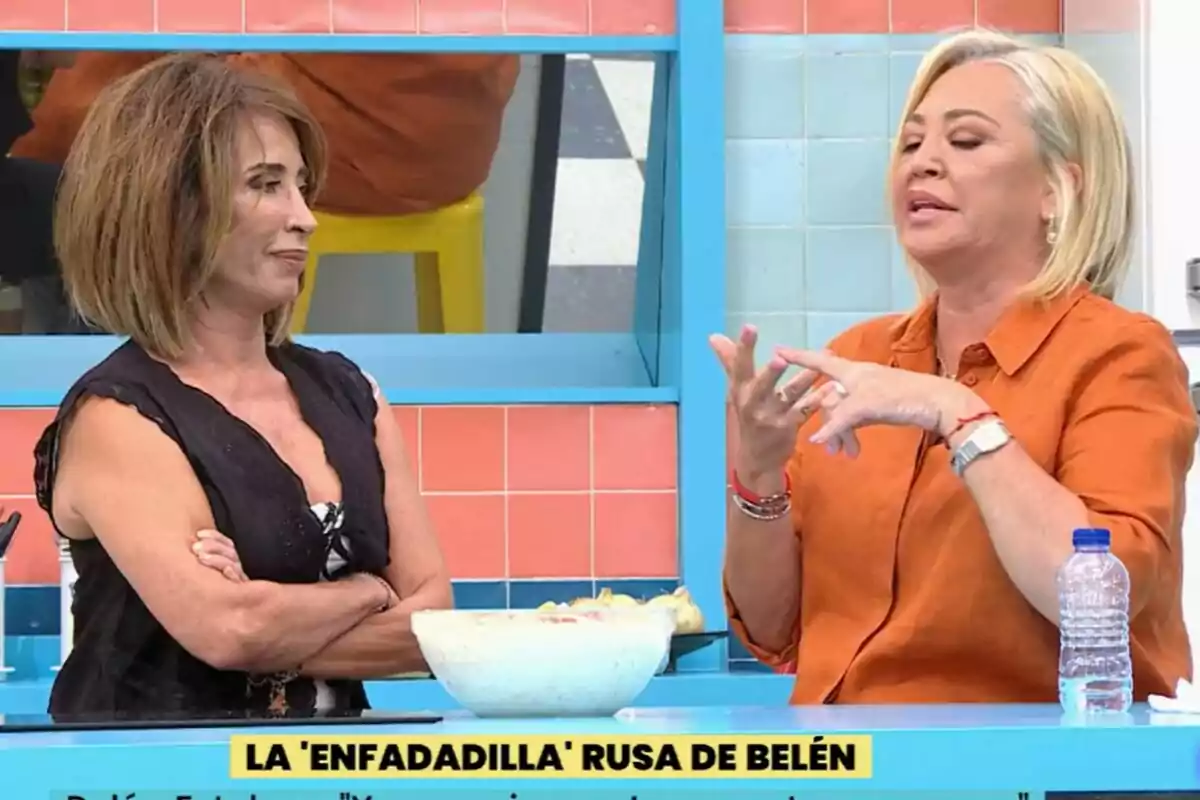 María Patiño i Belén Esteban conversen en una cuina a La Família de la Tele, una d'elles amb els braços creuats i l'altra gesticulant, amb un recipient d'amanida sobre la taula.