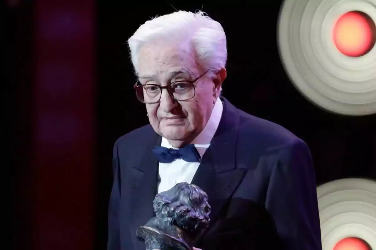Maríano Ozores gran amb ulleres i cabell blanc sosté un trofeu en un esdeveniment formal.