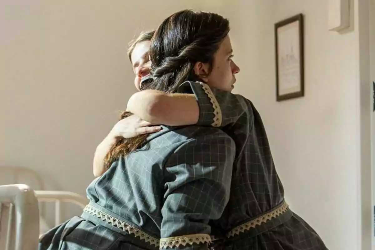 Fotografía de Martina y Juana vestidas con ropa de época se abrazan en una habitación iluminada en La Promesa Fotografía de Martina y Juana vestidas con ropa de época se abrazan en una habitación iluminada en La Promesa