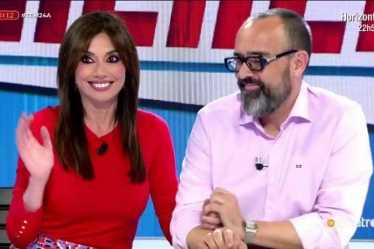 Risto Mejide i Marta Flich assegudes a Tot és Mentida, una dona somriu i saluda mentre un home amb barba i ulleres l'observa. Risto Mejide i Marta Flich assegudes a Tot és Mentida, una dona somriu i saluda mentre un home amb barba i ulleres l'observa.