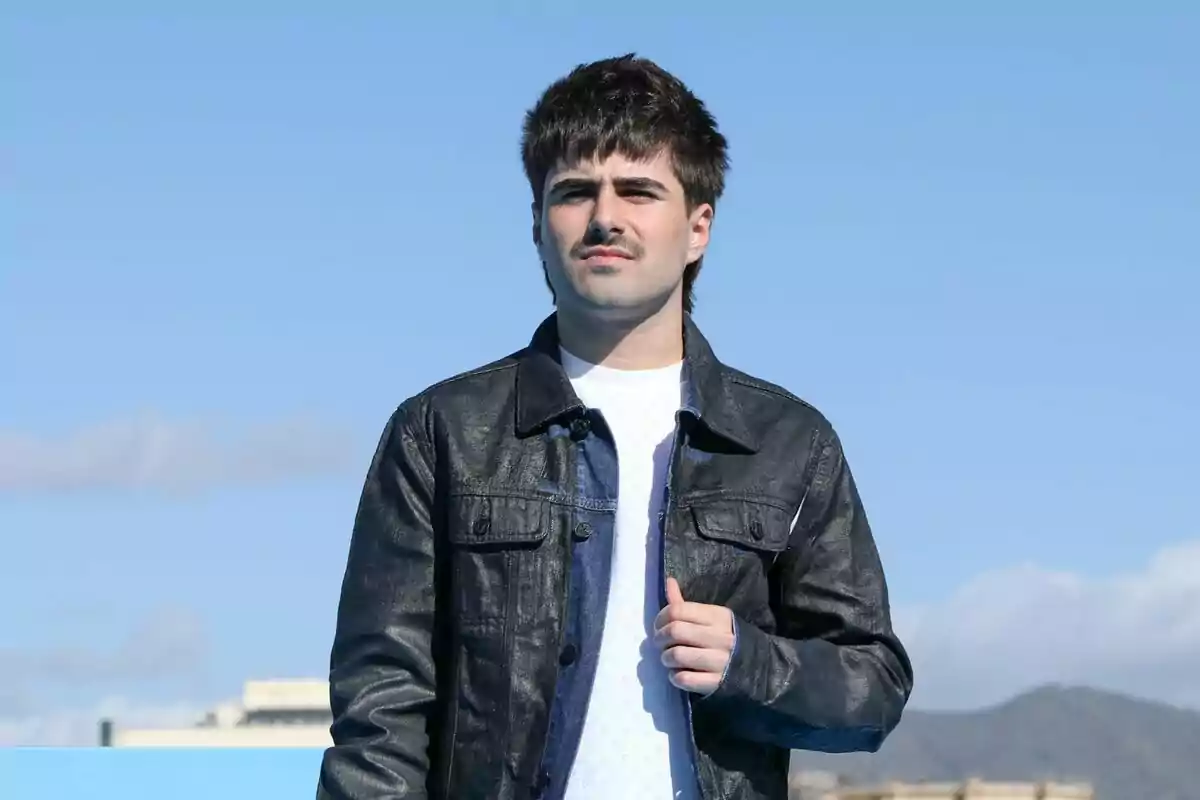 Martin Urrutia amb jaqueta de cuir negra i samarreta blanca està dret a l'aire lliure sota un cel blau com posat de Mariliendre.