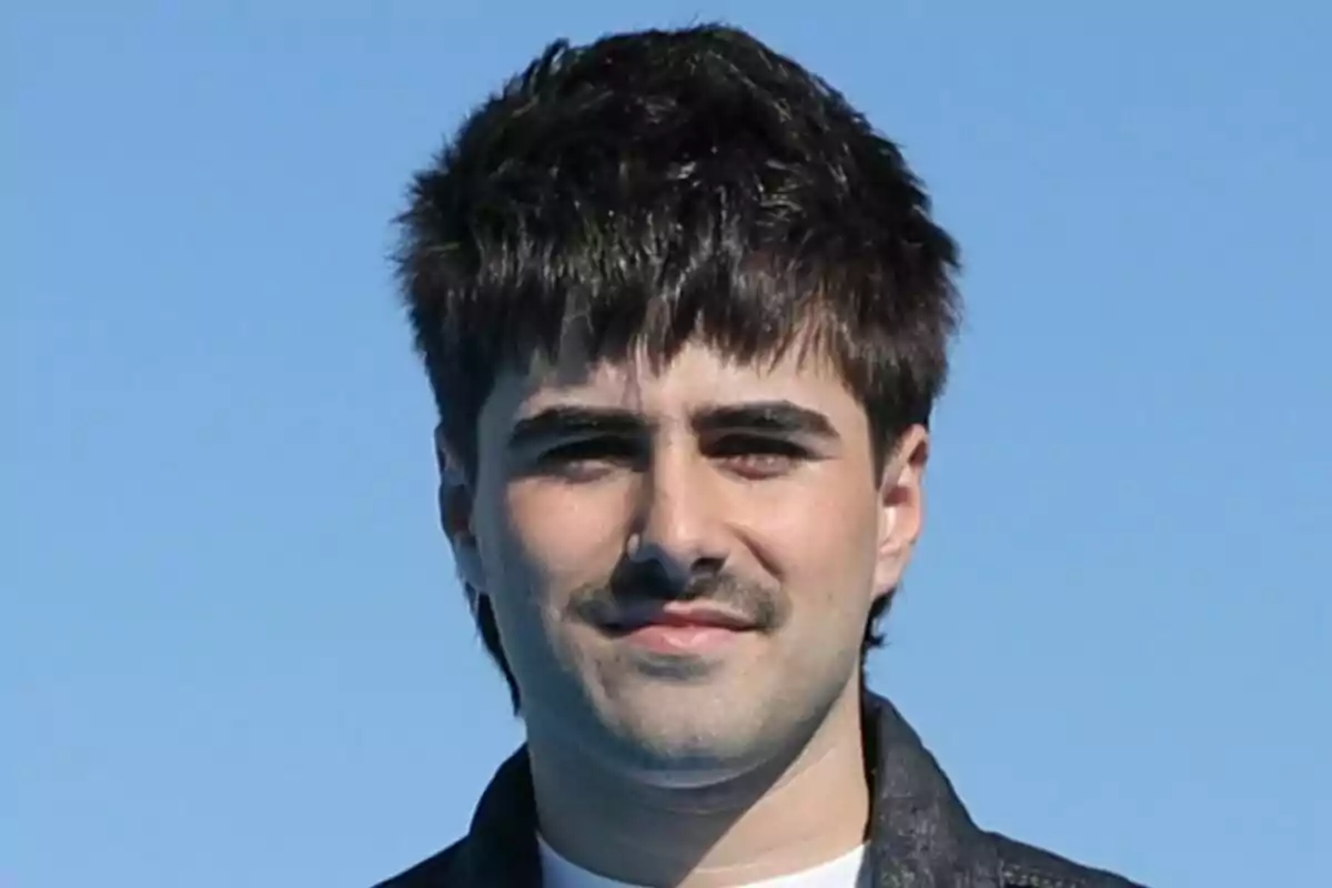 Martin Urrutia jove amb cabell fosc i bigoti, vestint una jaqueta negra, amb un cel blau de fons a Mariliendre.