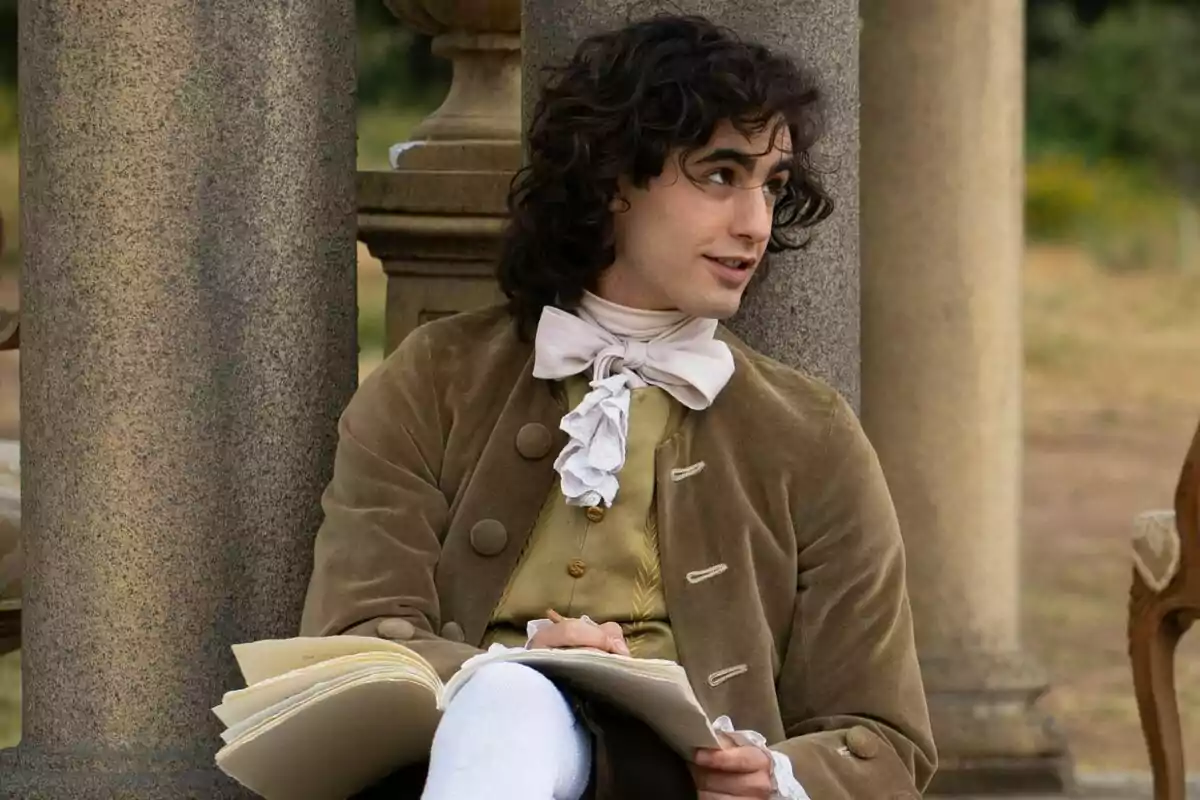 Plano medio del actor Mateo Jalón con vestimenta de época sentado junto a una columna sosteniendo un cuaderno. Plano medio del actor Mateo Jalón con vestimenta de época sentado junto a una columna sosteniendo un cuaderno.