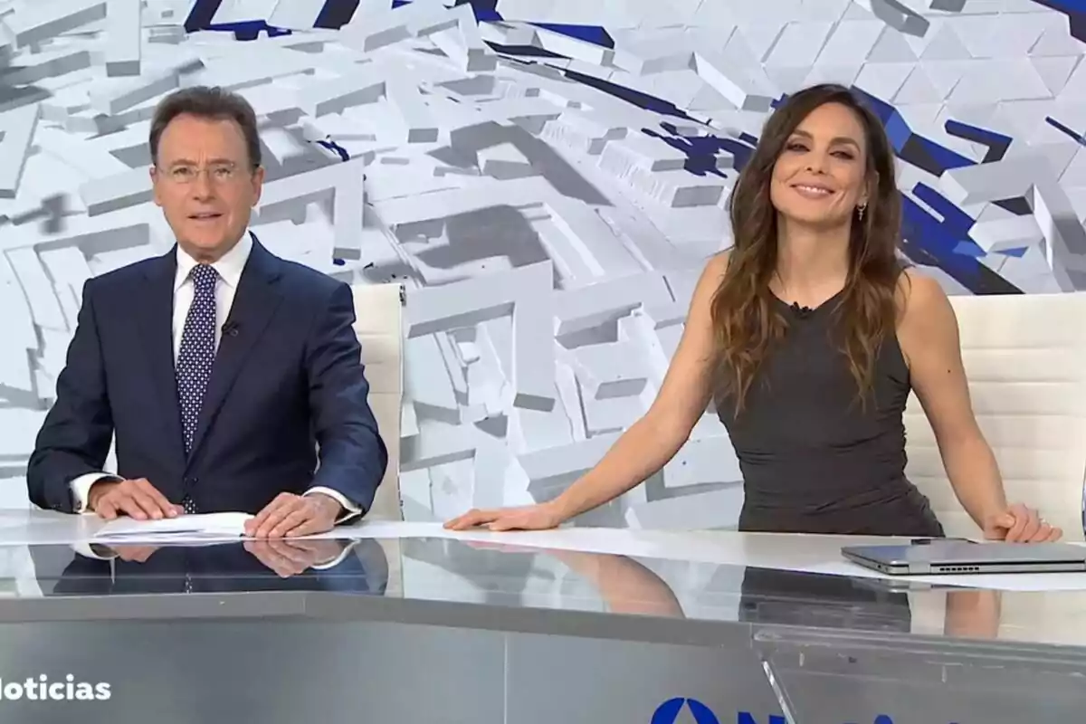 Captura de Matías Prats y Mónica Carrillo como presentadores de Antena 3 Noticias con un fondo geométrico blanco y azul. Captura de Matías Prats y Mónica Carrillo como presentadores de Antena 3 Noticias con un fondo geométrico blanco y azul.