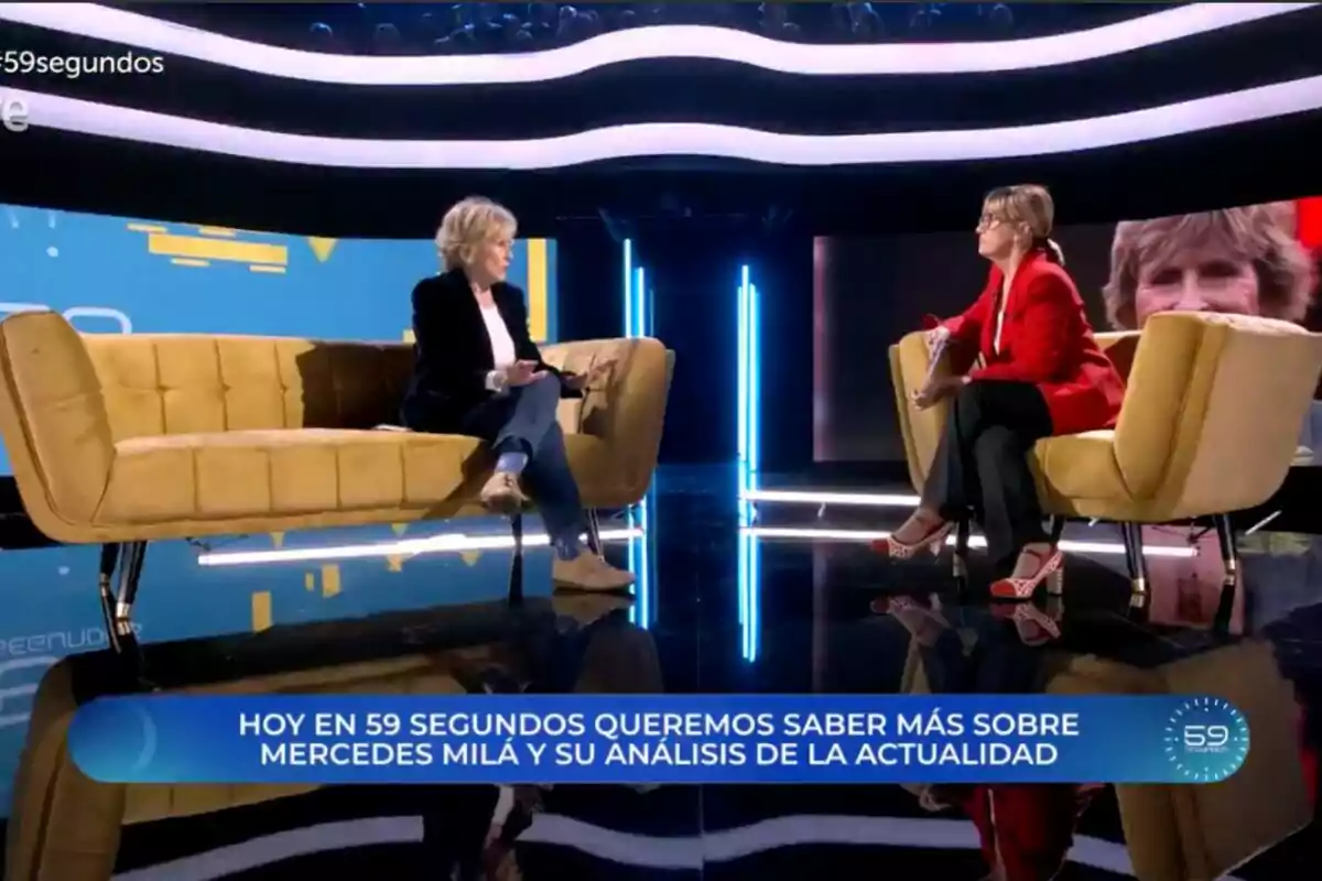 Mercedes Mila y Gemma Nierga sentadas en un set de televisión moderno con sofás amarillos y luces azules, conversando en un programa llamado Mercedes Mila y Gemma Nierga sentadas en un set de televisión moderno con sofás amarillos y luces azules, conversando en un programa llamado